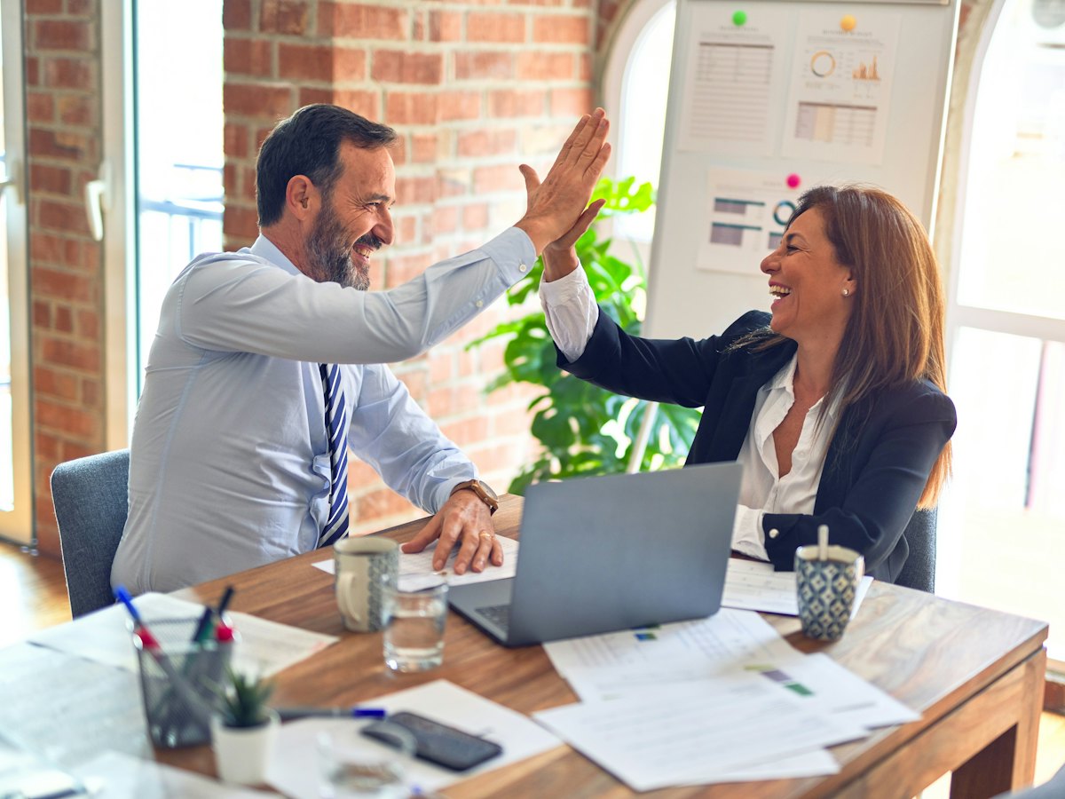 Two people celebrating a good deal at a desk